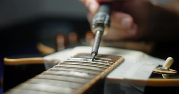 Luthier Heats Frets on Guitar By Soldering Iron Before Refretting Guitar Artisan's Preparations for