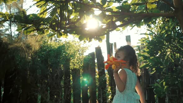 Happy Child Runs With A Toy Airplane On A Sunset Background