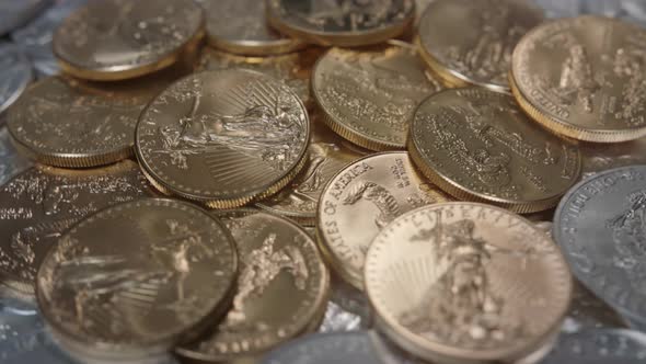 Gold American Eagles coins on a bed of silver coins rotating right