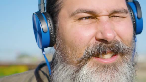 Bearded Middleaged Man with Headphones Listens to Music Sings Along and Nods to the Beat of the