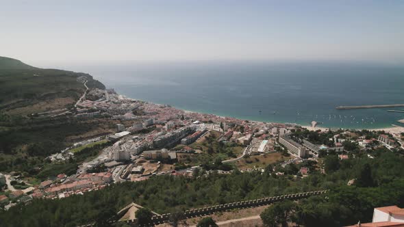 Aerial backward over castle walls and Santa Maria do Castelo church with Sesimbra city in background