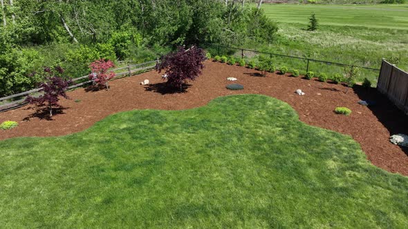 Aerial shot pushing through a backyard with a fresh layer of weed preventing bark.