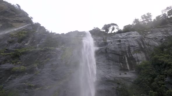 Slow motion shot of waterfalls crashing down a mountain face and into the water below