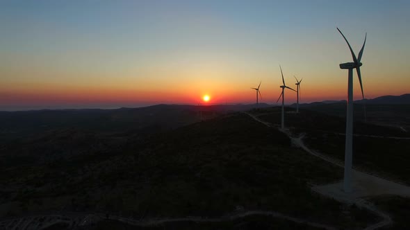 Aerial view of windmills with slowly rotating blades at sunset