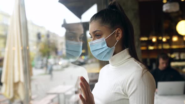 Young Woman in Face Mask Standing in Front of Windows in Cafe