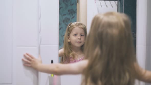 Young Lady Looks at Mirror Posing in Light Modern Bathroom