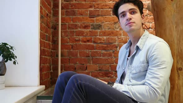 Young Man Waiting and Watching Time on Watch Sitting on Stairs