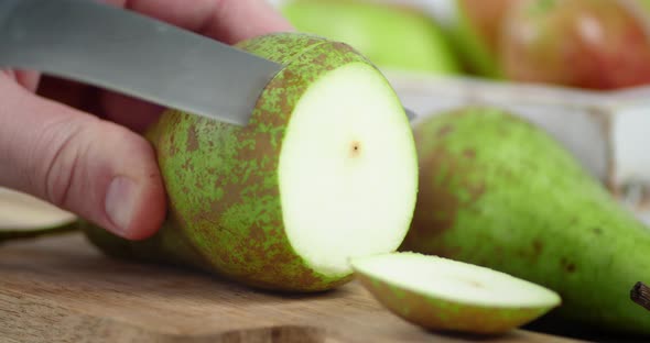 The Hand of a Man with a Knife Cut Into Round Slices of Pear. 