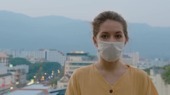 Portrait of a Beautiful Young Woman Wearing Protective Medical Face Mask and Standing on the Rooftop