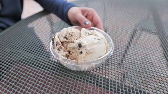 Close up shot of womans hand eating ice cream on metal table. High angle