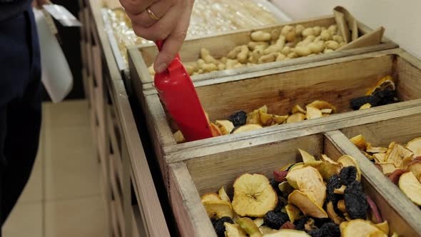 Closeup of a Salesman Pouring Dried Fruit Into a Box in a Grocery Store