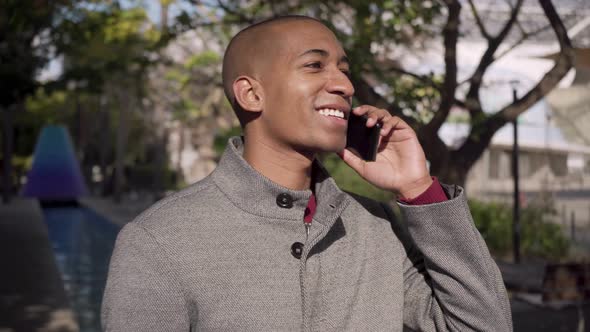 Man Talking By Cell Phone and Smiling on Street