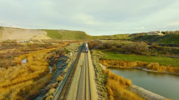 AERIAL - Train on railroad tracks close to Bluffdale, Utah, forward tracking shot