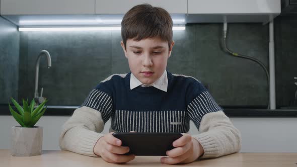 Portrait of Handsome Boy Playing Video Game with Smart Phone Indoors at Living Room