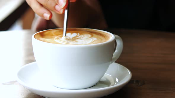 Person Hand Stirring Coffee with Spoon