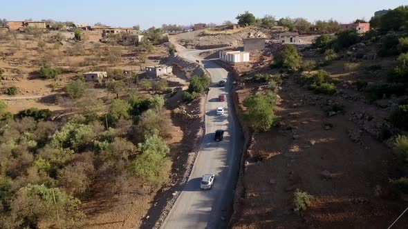 Drone view of the vehicles travelling through a mountainous road; winding roads in the mountains or