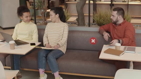 Man Starting Conversation with Women in Cafe