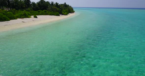 Daytime birds eye tourism shot of a sandy white paradise beach and blue sea background in hi res 4K