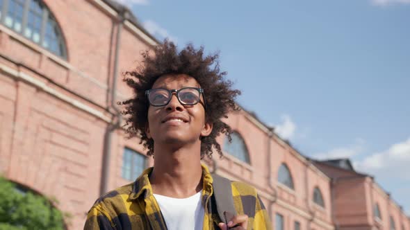 Close Up Portrait of Young African American Man with Curly Hair Smiling and Looking Away Outdoors