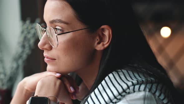 Happy young brunette woman in eyeglasses looking at the camera