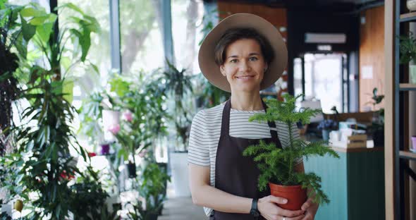 Portrait of Good-looking Girl Holding Houseplant Standing in Flower Shop