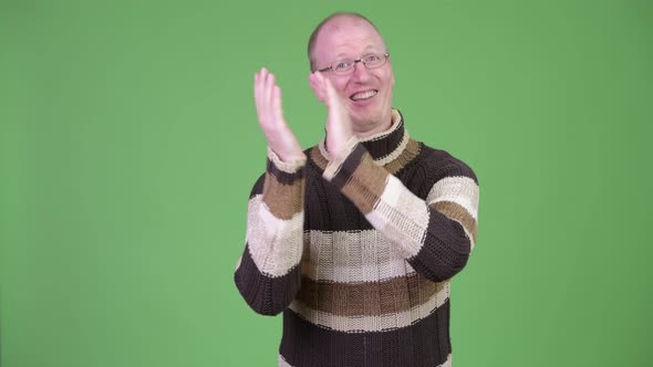 Happy Mature Bald Man with Turtleneck Sweater Clapping Hands