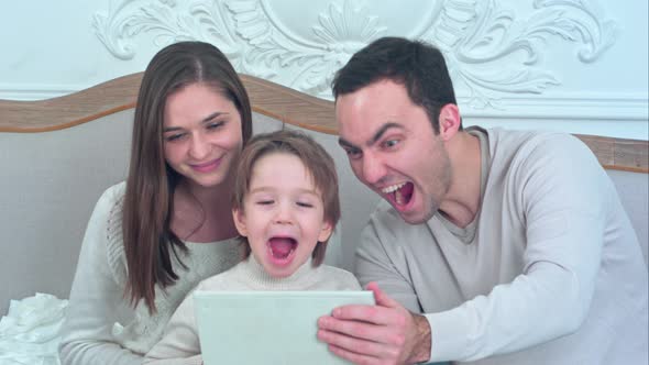 Young Happy Family Watching Their Photos on the Tablet and Laughing