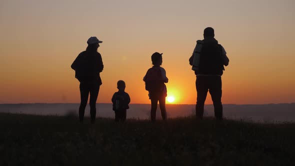 Parents and Two Children Walking in the Mountains at the Sunset Time. Silhouette Happy Beautiful