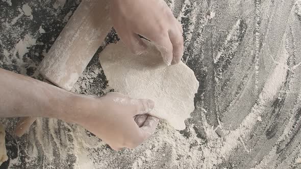 Hands Roll Out Baking Dough Using Rolling Pin on a Wooden Board