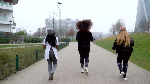 Slow motion of three sportive young women jogging in the city