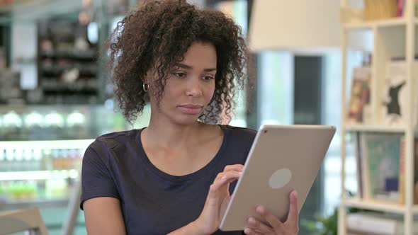 Portrait of Young African Woman Celebrating Success on Tablet 