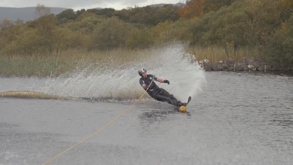 Young slalom skier waterski cuts around buoy