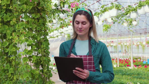 Female Agronomist Checking the Cultivation of Fresh Flowers Taking Notes