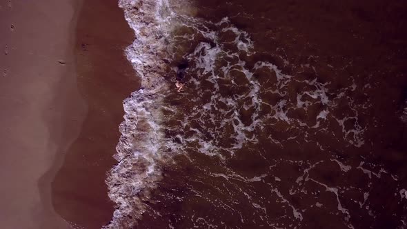 AERIAL with Sandy Beach of Baltic Sea and Child Jumping in Water  Top View