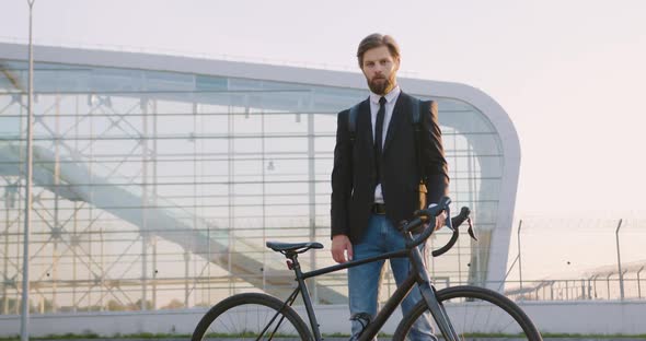 Office Worker Posing Near His Bicycle on the Big Glass Construction Background 