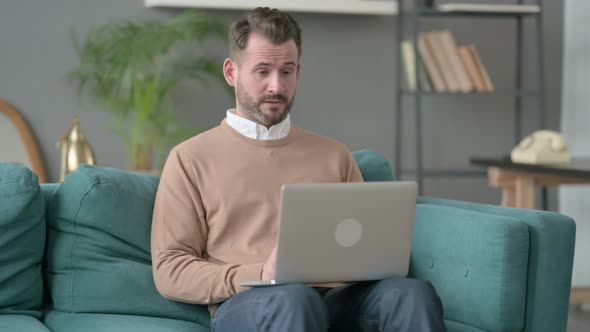 Man Crying While Working on Laptop on Sofa