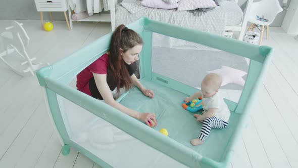 Baby Girl Playing with Beloved Mother in Playpen