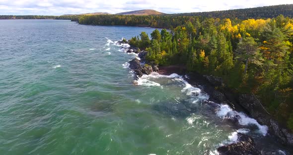 Aerial Across Lake Next to Rocky Coast and Fall Trees