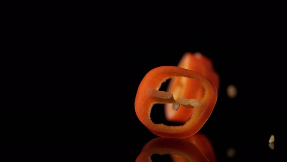 Sliced red chili pepper falling on water surface. Slow Motion.