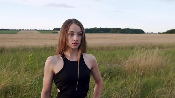 Portrait of Attractive Young Sports Girl Looks Purposefully at Camera on Nature