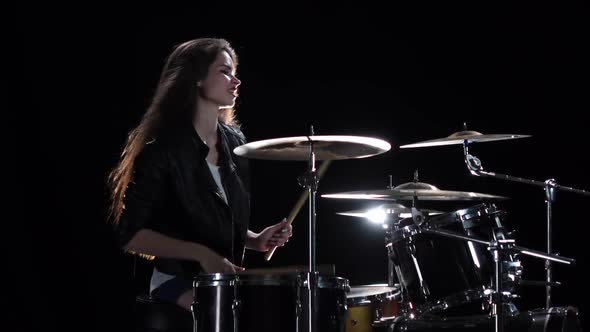 Girl Drummer with Chopsticks Beats Rhythmic Music. Black Background. Side View. Slow Motion