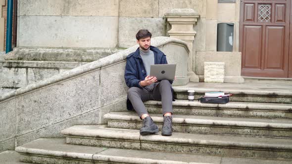 Man using laptop while sitting on stone staircase