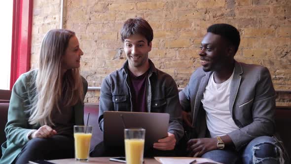 Happy friends working together with a laptop on a break, slow motion