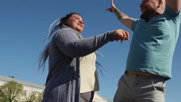Two Young Happy People Dance on Background of Bright Blue Sky. Body Positive Fat Friends Enjoy Life