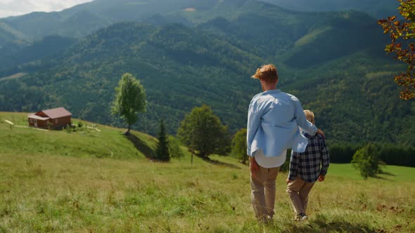 Father Hugging Son Walking on Mountain Hill