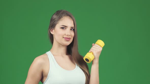 Happy Beautiful Sportswoman Holding Dumbbell and a Bottle of Water Smiling