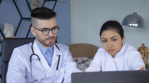 Close up of a Man and a Woman A Doctor and a Nurse Working at a Computer in the Hospital Office