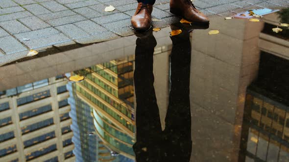 Reflection of a businessman in the puddle using digital tablet