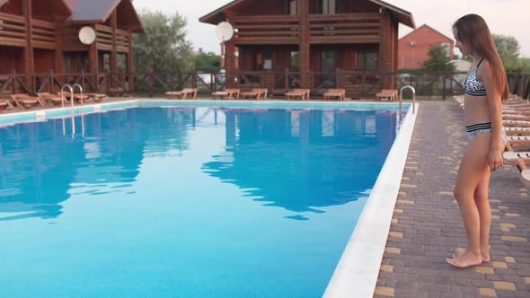 Girl in a Leopard Print Swimsuit Spends Time in the Pool Jumping Into It