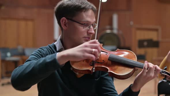 a guy and a young woman, they play violins during a string concert